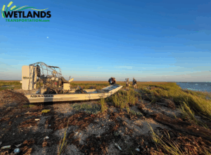 Airboat on marsh shoreline with crew during coastal transport