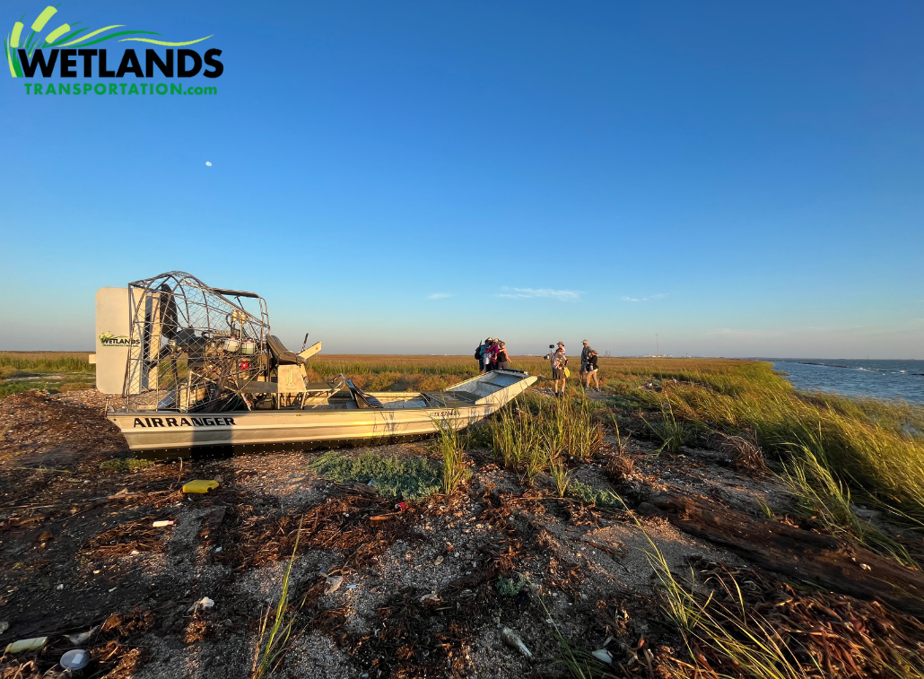Airboat on marsh shoreline with crew during coastal transport